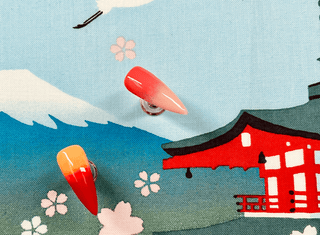 two ombre red and orange nails against a japanese background.